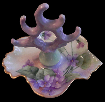 European hard paste porcelain ring holder decorated with a floral decal and gold gilt. Printed mark “Victoria Carlsbad Austria” dates 1891-1918. Similar example shown right.